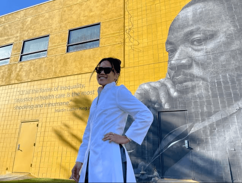 Person posing in front of large mural.