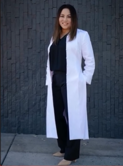 Person wearing a white coat, smiling outdoors.