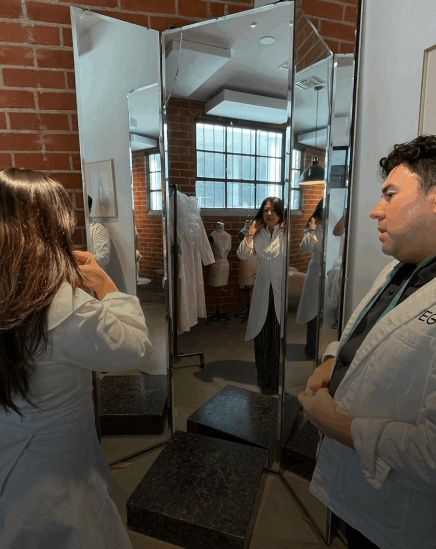 People in lab coats by mirror.